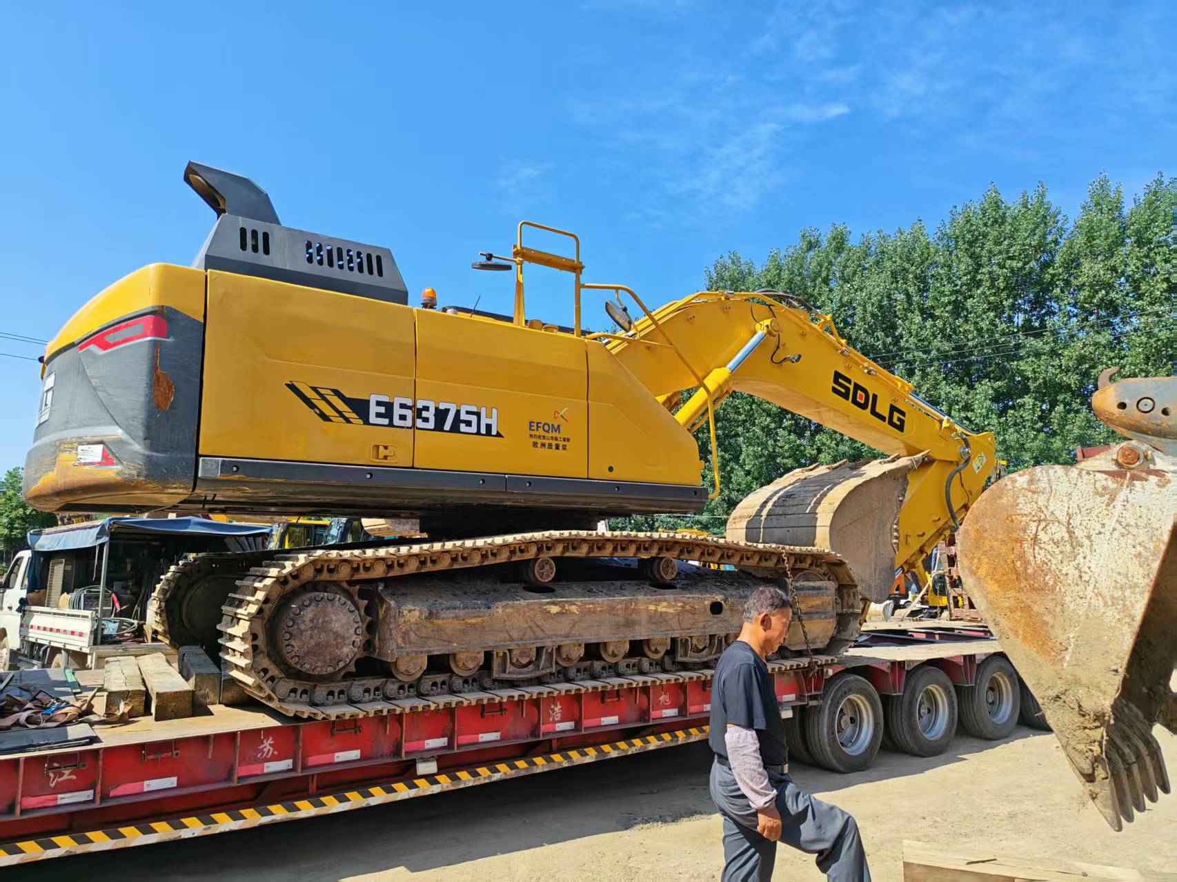 Large SDLG crawler excavator on a multi-axle trailer for yard-to-port movement.
